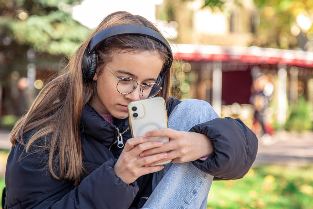 Niña mirando el móvil con cascos puestos