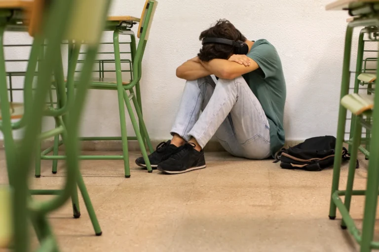 Chico solo con la cabeza entre las rodillas